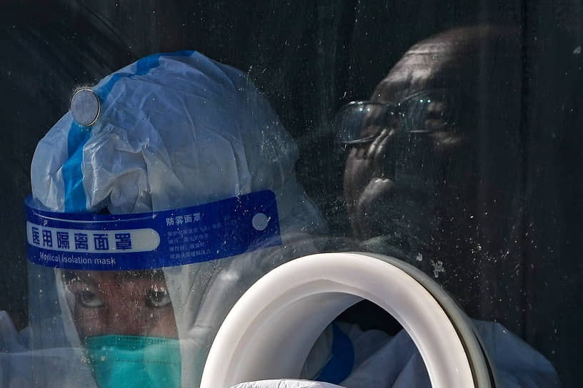 Пекин, Китай. Медицинский работник в защитном снаряжении берет образец у местного жителя для тестирования на коронавирус
