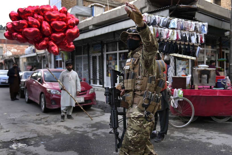 Кабул, Афганистан. Уличный торговец со связкой шаров в форме сердец рядом с бойцом движения «Талибан» (признано в РФ террористическим и запрещено)