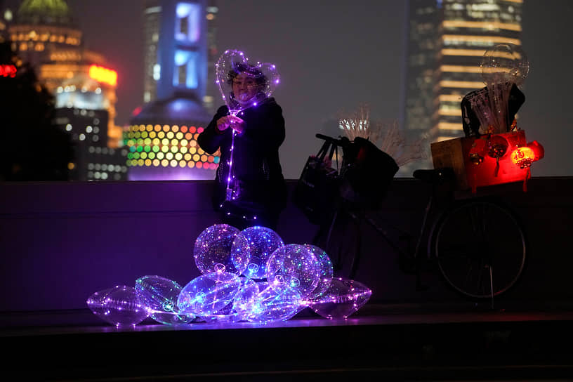 Шанхай, Китай. Женщина продает светящиеся воздушные шары
