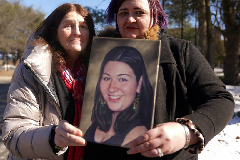 Родственницы погибшей в результате стрельбы с ее портретом