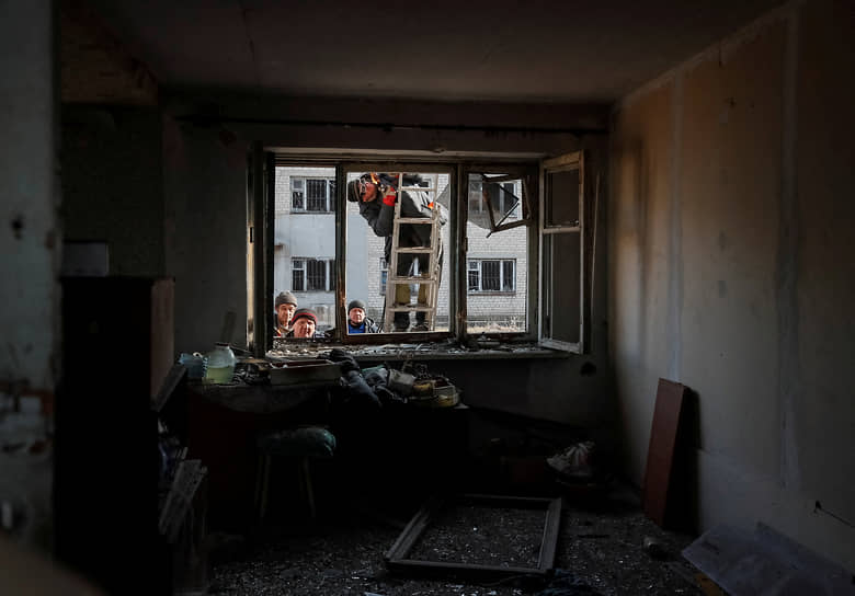 Рабочие в Новолуганске смотрят в окно разрушенного дома