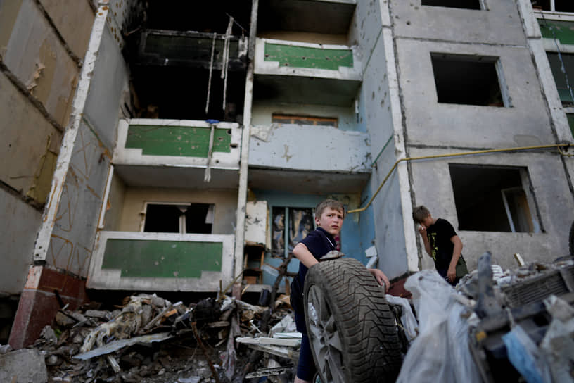 Мальчики стоят возле здания, разрушенного в результате обстрелов в Чернигове