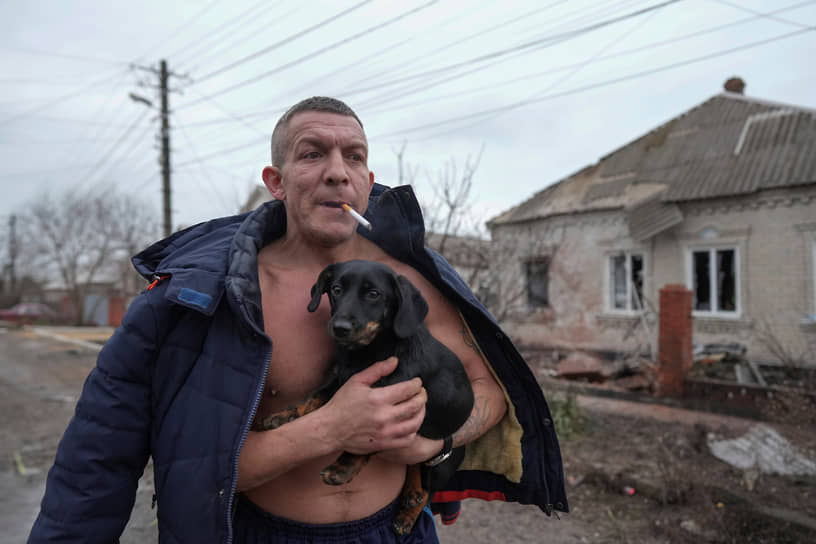 Мужчина с собакой около разрушенного дома в Мариуполе