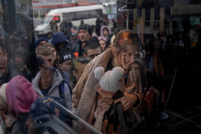 Женщина с ребенком садится в автобус, уезжающий из Киева