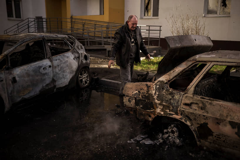 Мужчина смотрит на свою сгоревшую машину в Харькове