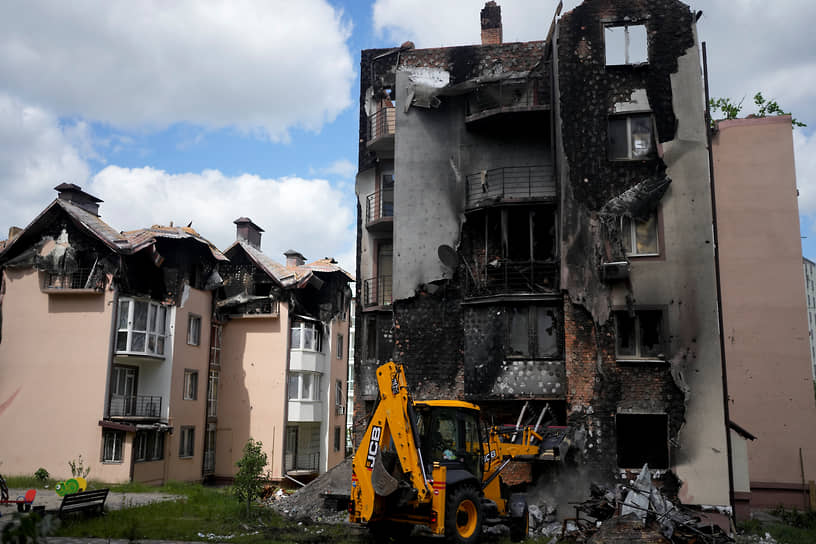 Экскаватор убирает завалы уничтоженного в результате обстрелов здания в Ирпене на окраине Киева