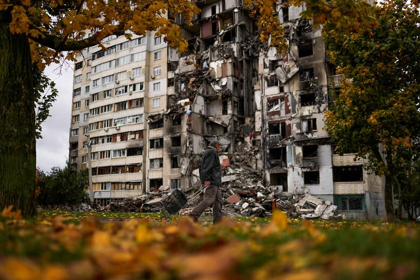 Мужчина с тележкой проходит мимо разрушенного жилого дома в Харькове