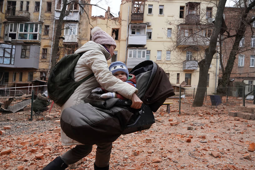 Женщина несет ребенка во время эвакуации в центре Харькова 