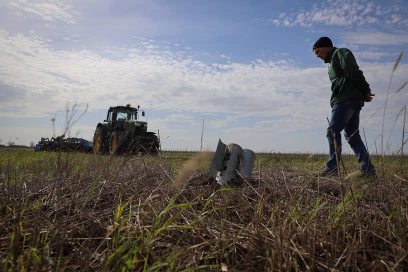 Фермер смотрит на часть российской ракеты на сельскохозяйственном поле в Запорожской области