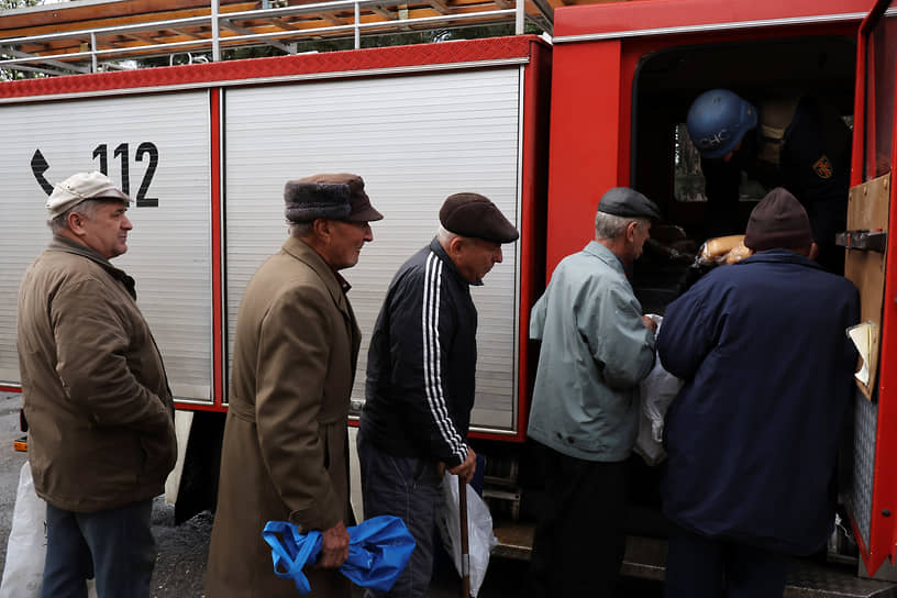 Мужчины стоят в очереди за хлебом в пункте раздачи гуманитарной помощи в Орехове