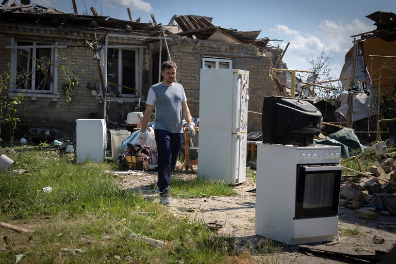 Местный житель выносит вещи из разрушенного дома в селе Старые Петровцы под Киевом
