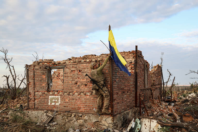 Украинский военнослужащий поднимает флаг страны в прифронтовом селе Андреевка