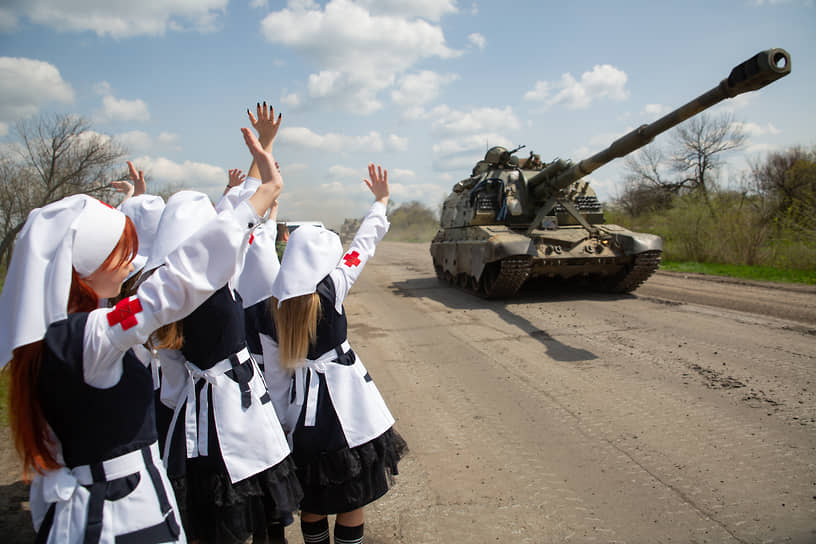 Луганские активисты молодежного движения «Сестры Победы» машут проезжающим на самоходной гаубице 2С19 «Мста-С» военнослужащим РФ