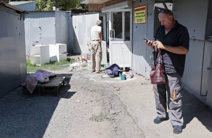 Мужчины у тела женщины, погибшей в результате обстрела Кировского района Донецка 