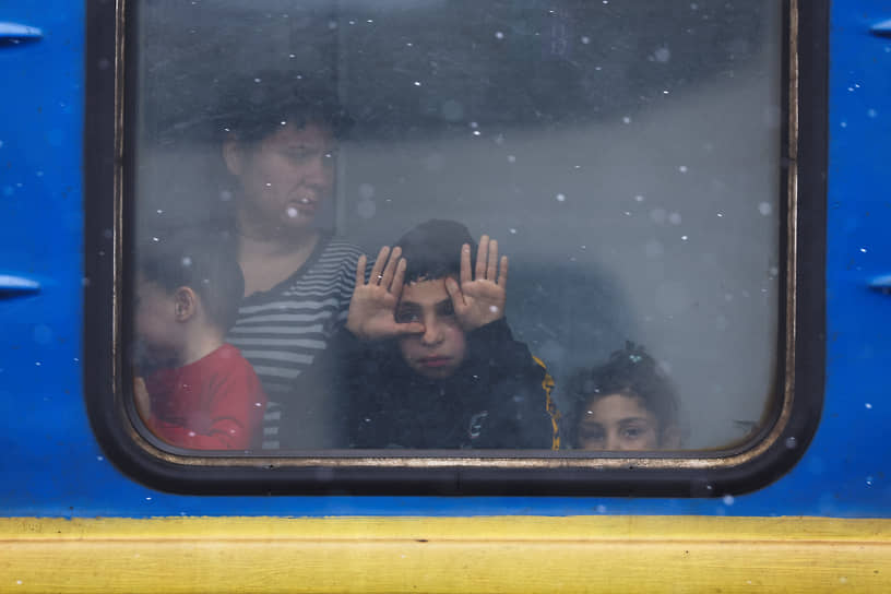 Мальчик смотрит через стекло поезда, отправляющегося из Львова в Польшу