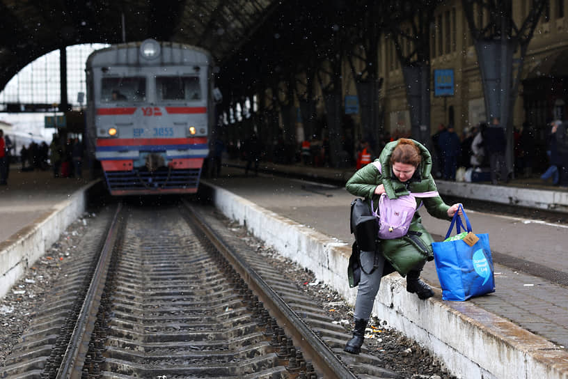 Женщина идет к поезду через железнодорожные пути