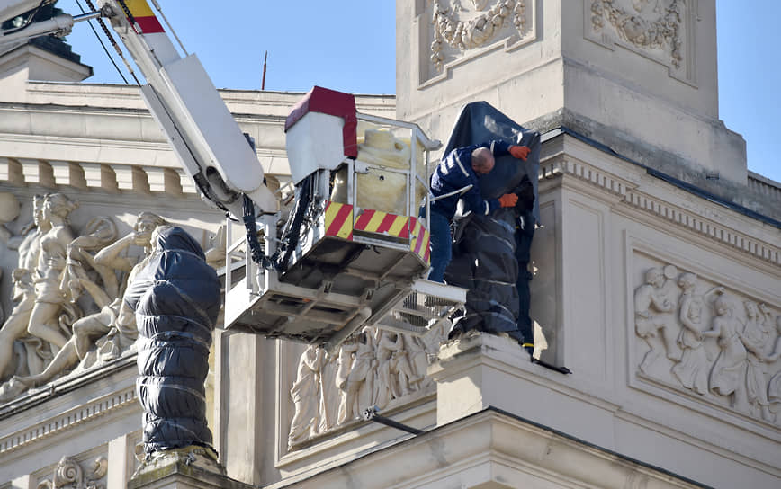 Рабочие укрывают скульптуры на фасаде Львовской национальной оперы для защиты от повреждений