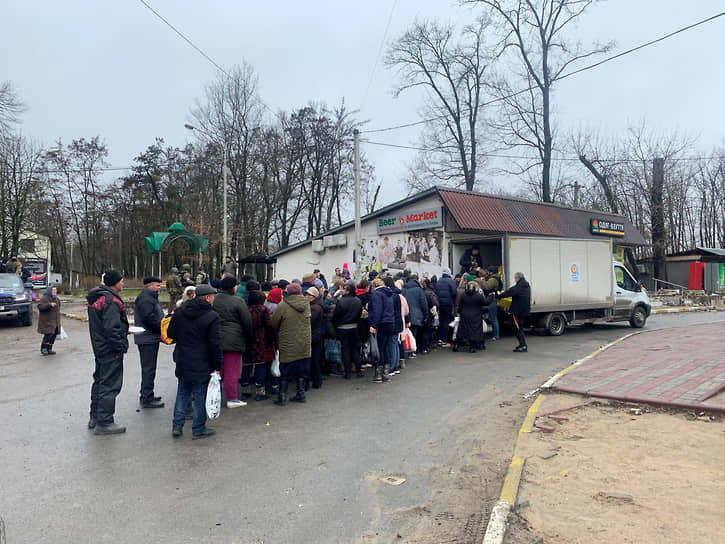 Местные жители в очереди у машины с гуманитарной помощью  в городе Буча в Киевской области