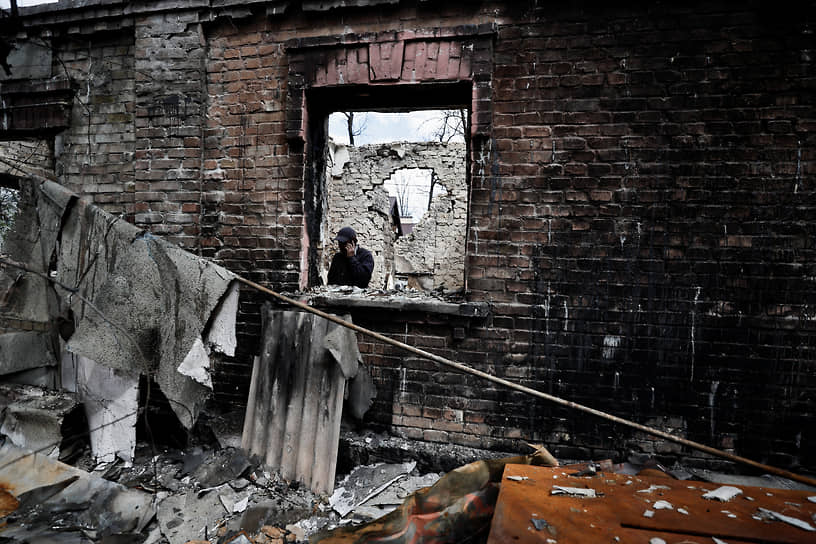 Местный житель разговаривает по телефону в разрушенном доме под Киевом