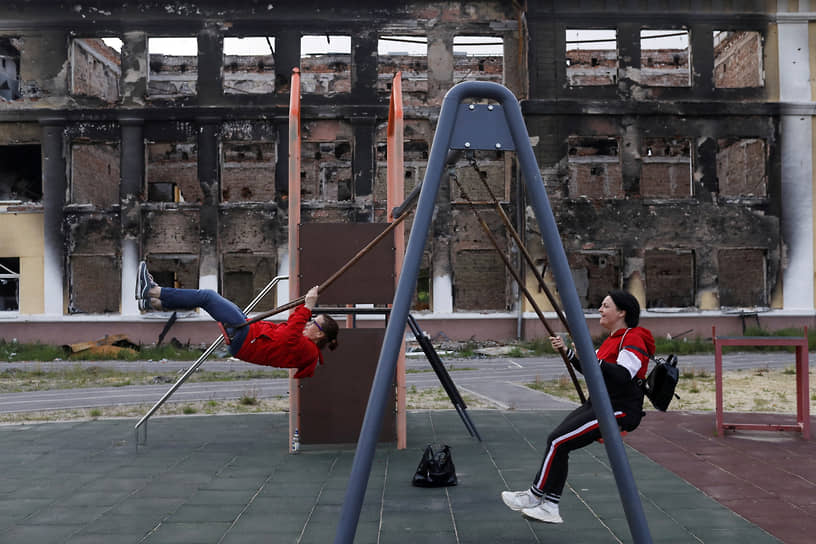 Местные жители катаются на качелях на детской площадке уничтоженной школы в Харькове