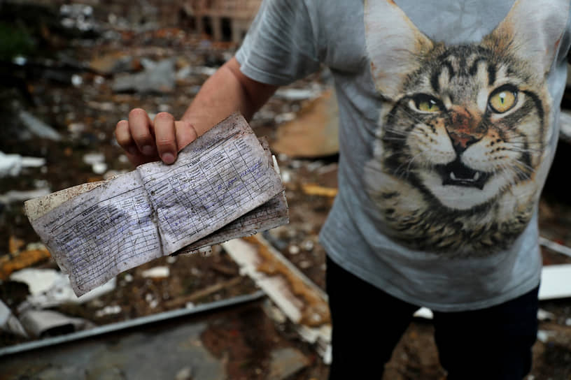 Мужчина показывает зачетку, найденную в разрушенном здании Харьковского национального университета