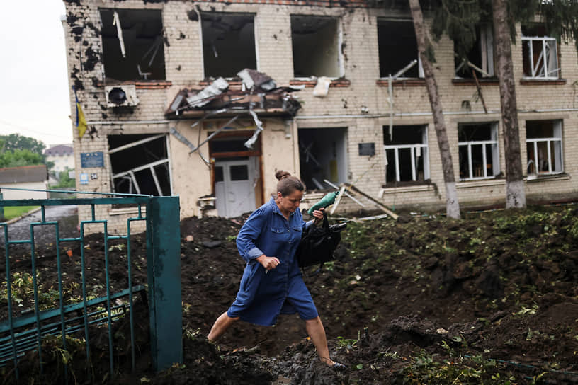 Учительница идет рядом с разрушенной школой в Чугуеве Харьковской области