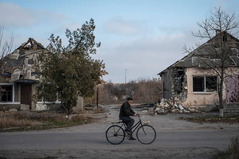 Местный житель едет на велосипеде мимо разрушенных домов в селе Архангельское Херсонской области
