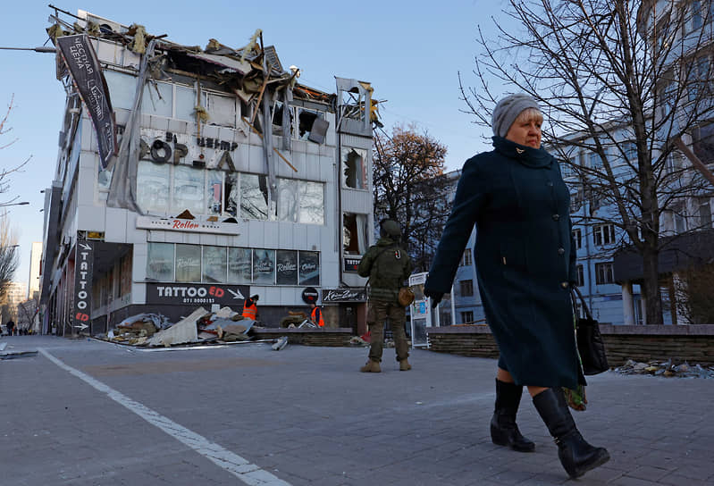 Женщина проходит мимо офисного здания, поврежденного в результате обстрела в Донецке