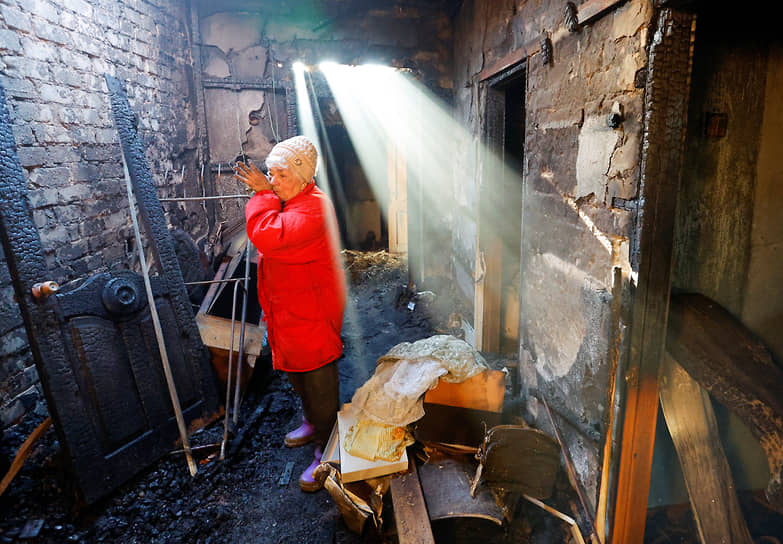 Жительница поселка Оленовка под Донецком в сгоревшем из-за обстрела доме 