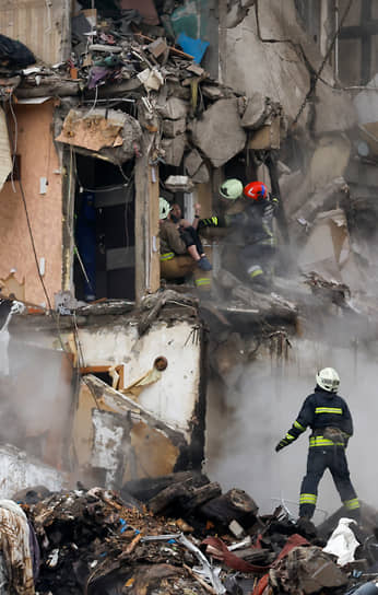 Спасатели эвакуируют женщину из дома, пострадавшего в результате взрыва ракеты в Днепре 