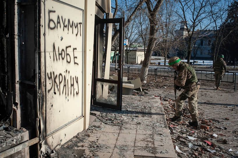 Украинский военный осматривает поврежденное здание в Бахмуте