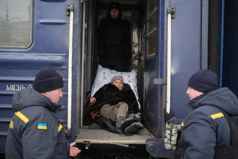 Мужчины помогают пенсионерке забраться в эвакуационный поезд неподалеку от Бахмута