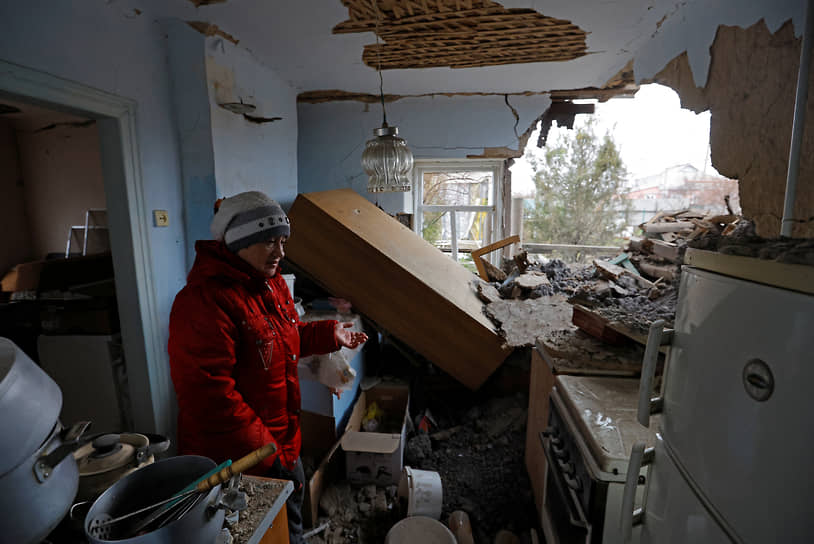 Жительница Горловки стоит в своем доме, разрушенном при обстреле