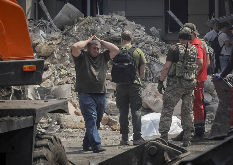Люди рядом с телом, лежащим около разрушенного здания в центре Одессы
