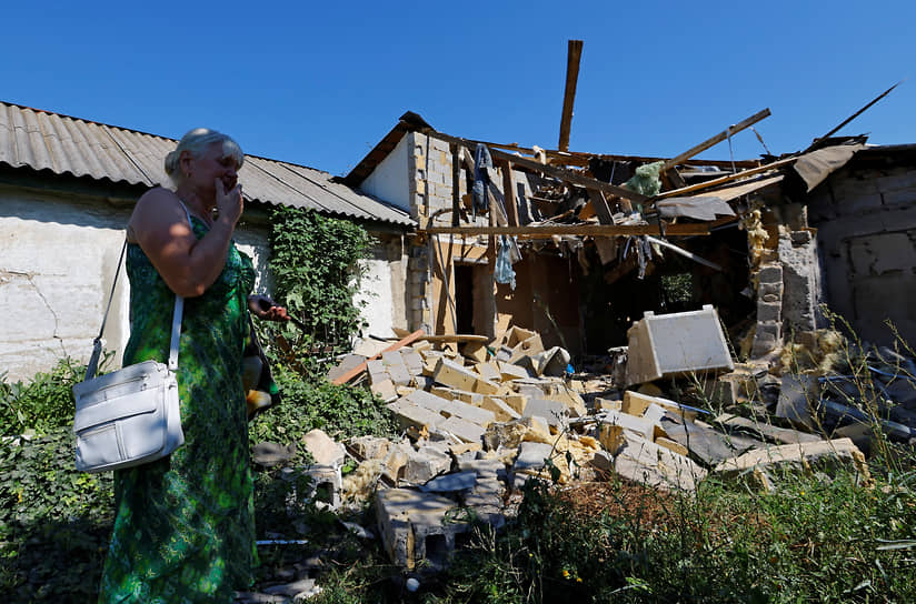 Жительница Донецка стоит рядом с разрушенным домом своего сына