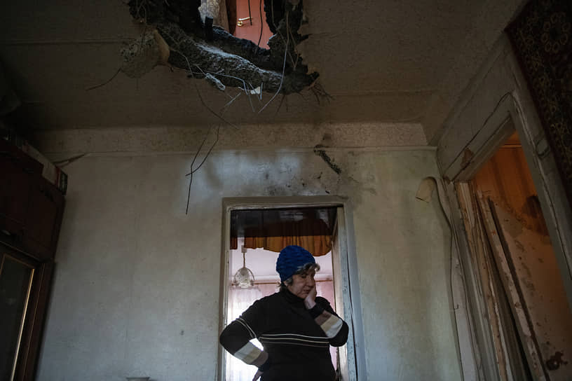 Жительница Донецка стоит внутри своей квартиры, поврежденной в результате обстрела