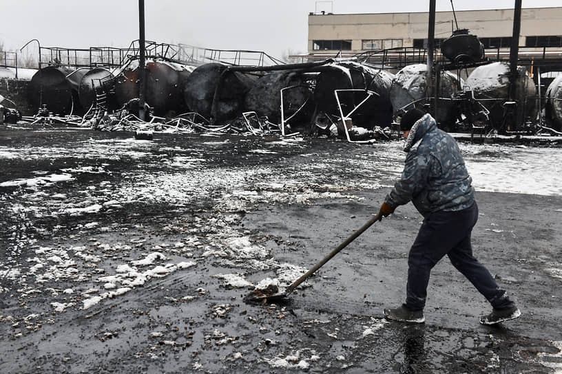 Мужчина собирает нефть на пострадавшей во время обстрела нефтебазе в Донецке
