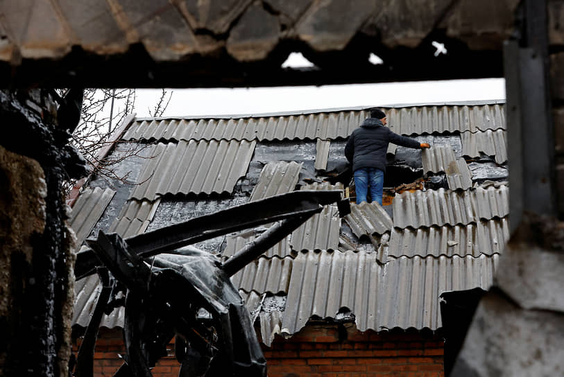 Человек на поврежденной в ходе обстрела крыше в Ясиноватой