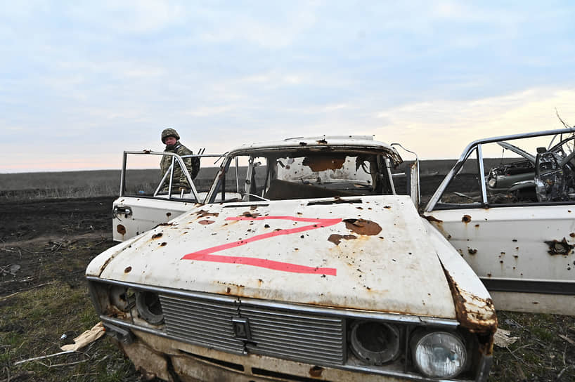 Украинский военнослужащий осматривает подбитую российскую машину возле села Роботино