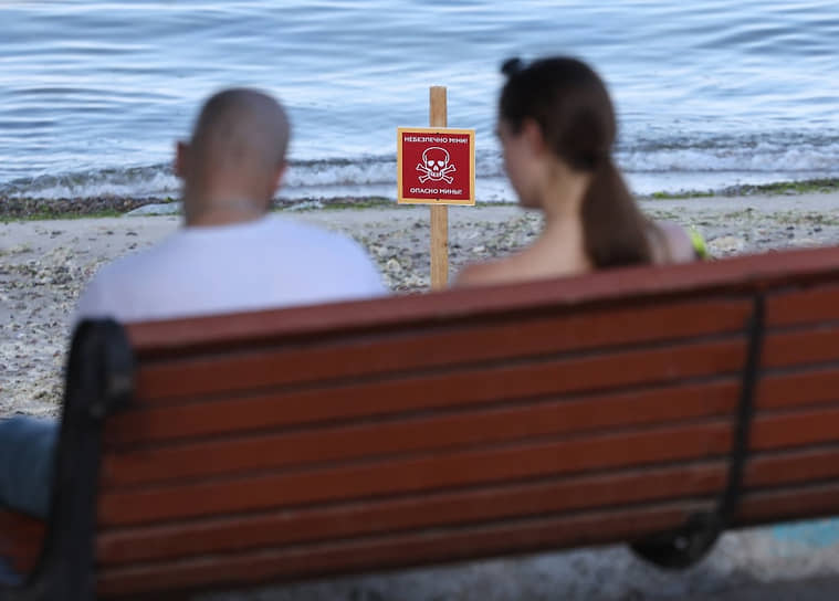 Пара на берегу моря на фоне таблички «Опасно мины!» в Одессе