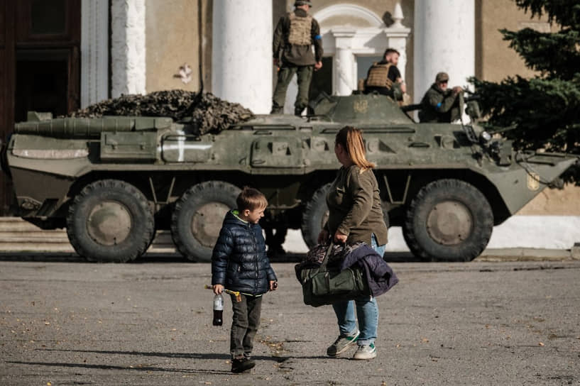 Жительница Купянска оглядывается на украинских военнослужащих на бронетранспортере 