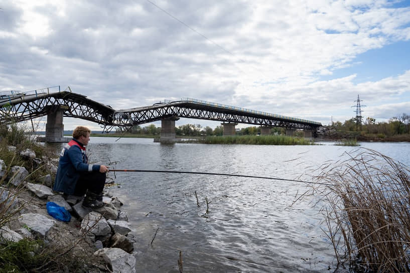 Мужчина ловит рыбу возле поврежденного моста в Сватово