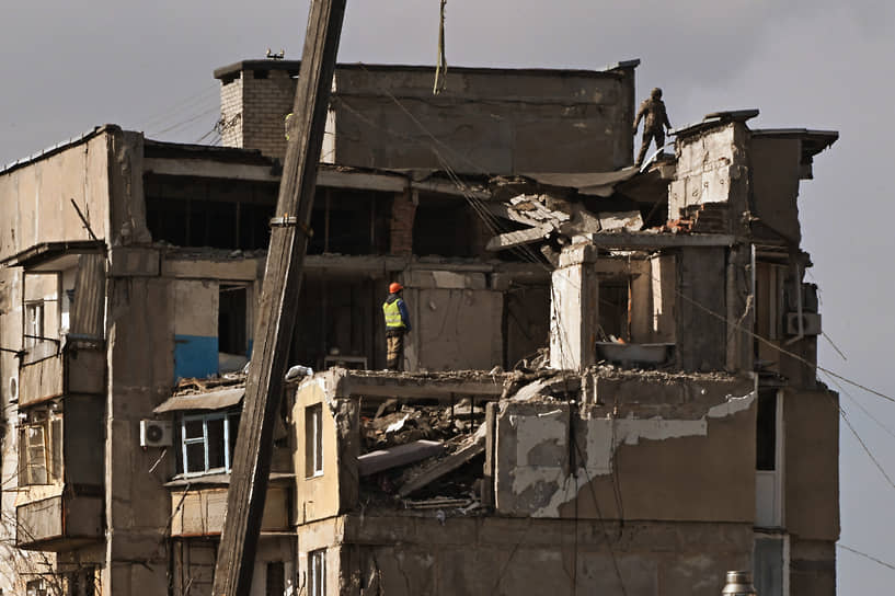 Рабочие на крыше разрушенного здания в Мариуполе 