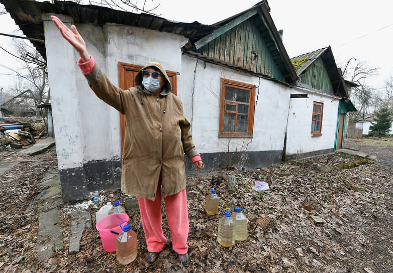 Женщина с бутылками воды у жилого дома