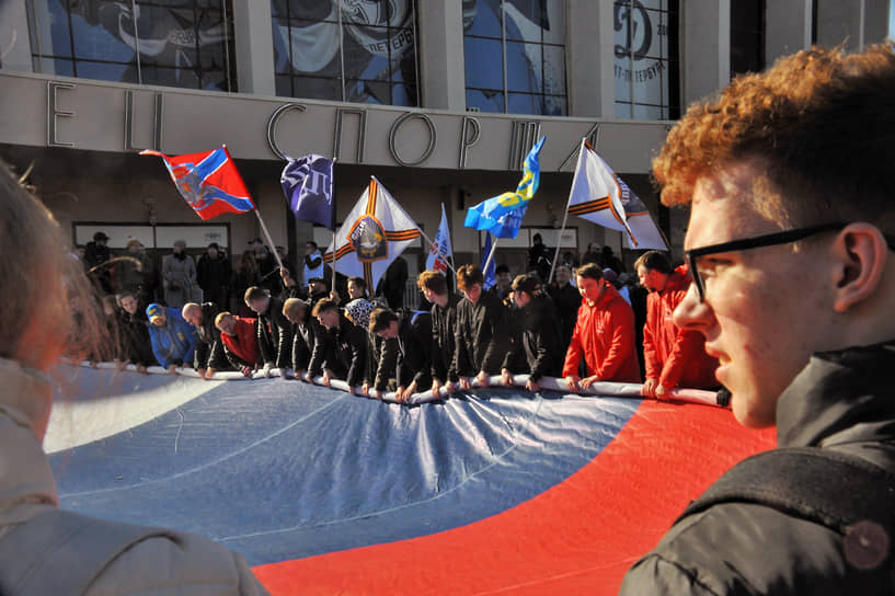 Люди растягивают российский флаг около спортивного комплекса «Юбилейный» в Санкт-Петербурге 