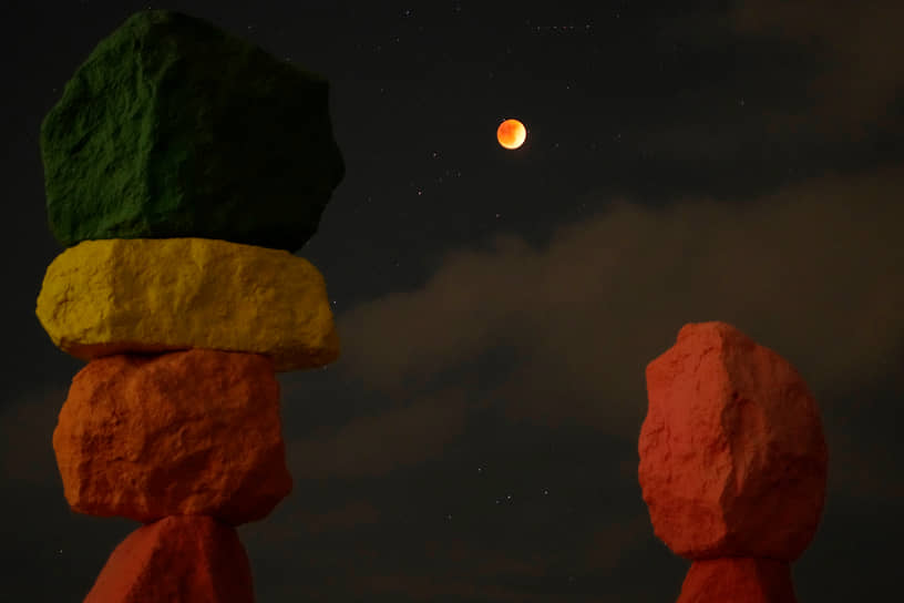 Жан, США. Арт-объект художника Уго Рондиноне «Семь волшебных гор» на фоне лунного затмения