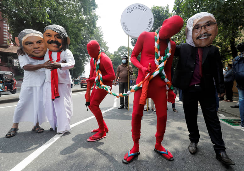 Демонстранты в масках трех братьев Раджапакса (слева направо) — президента Готабайи, премьер-министра Махинды и министра финансов Бэзила. Фигуры в красном символизируют государственную нефтяную компанию, а веревка в цветах индийского флага — Индию, которая душит экономику Шри-Ланки. 18 марта 2022 года