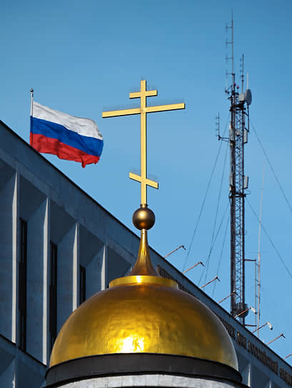 Москва. Крест на куполе церкви, флаг России и вышка сотовой связи