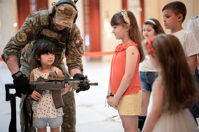 Бухарест. Девочка позирует с оружием на стенде румынской армии в Дворце парламента