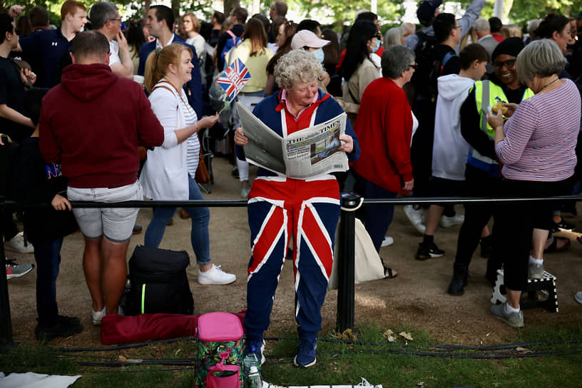 Британка читает газету возле Букингемского дворца во время празднований